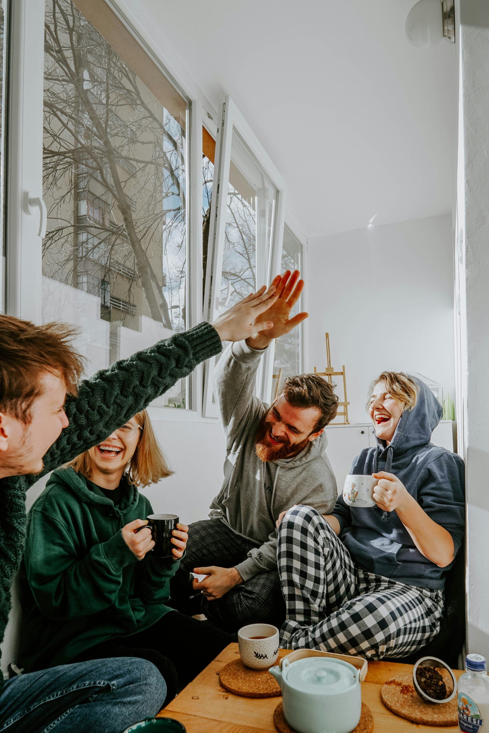 Young people laughing and having coffee together in an apartment