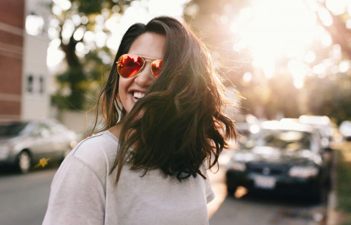Young woman wearing sunglasses crossing a neighborhood street
