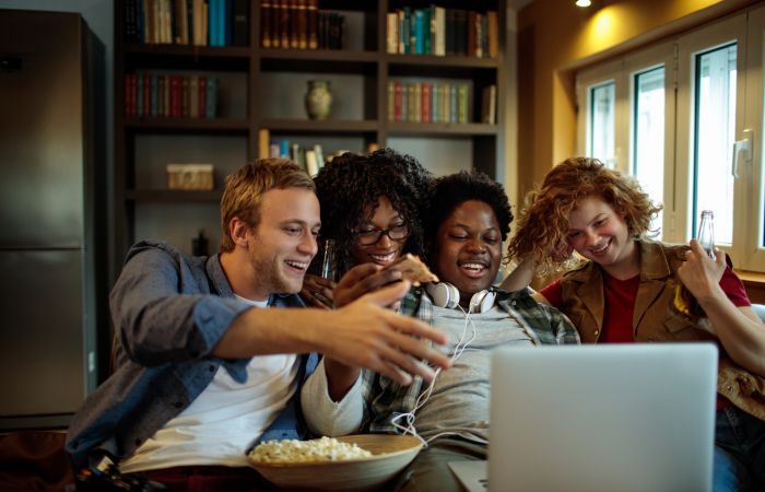 Group of friends enjoying a movie night at home with snacks and drinks