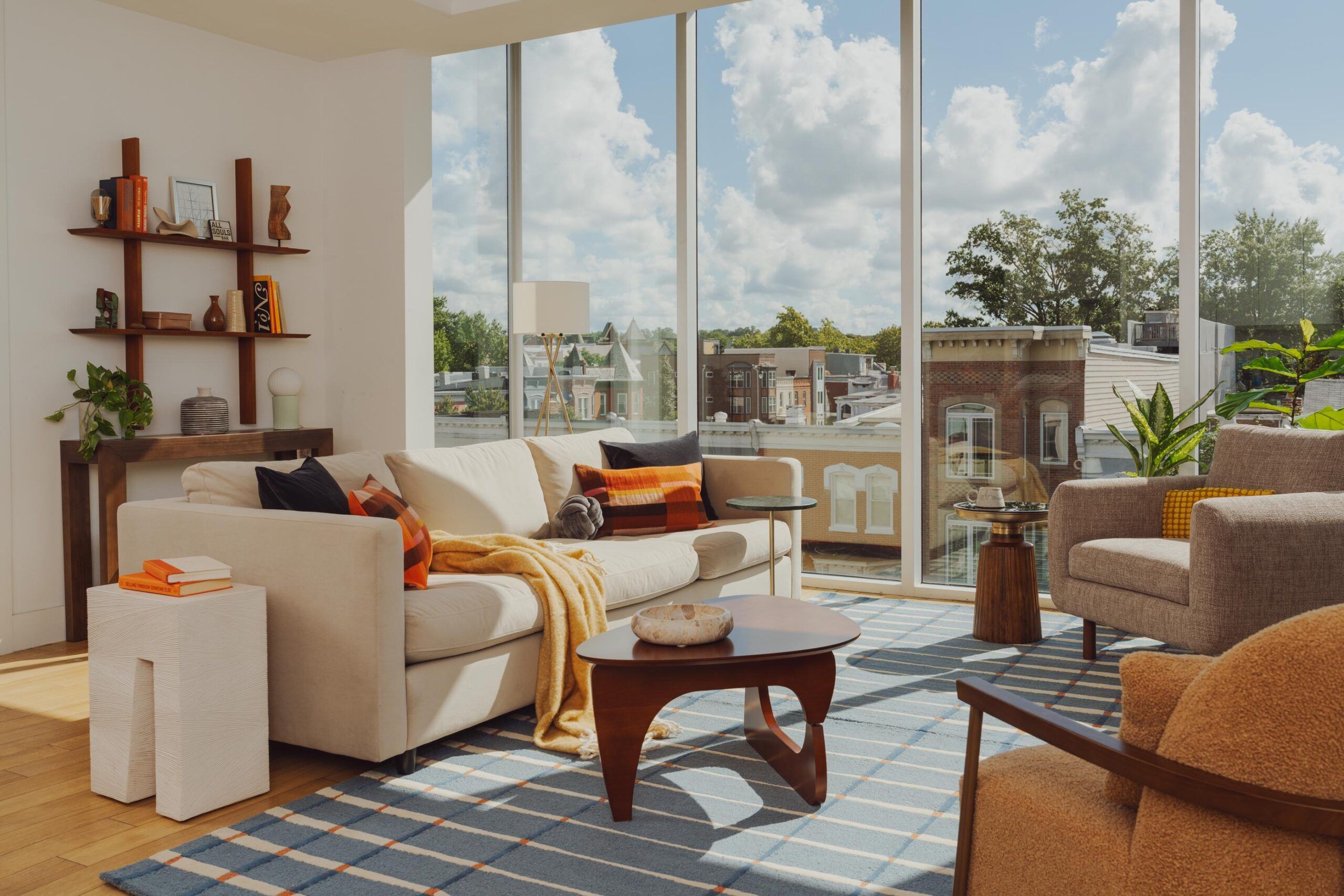 OSLO Coliving modern living room with large windows, beige sofa, accent chairs, and sunlight streaming in.