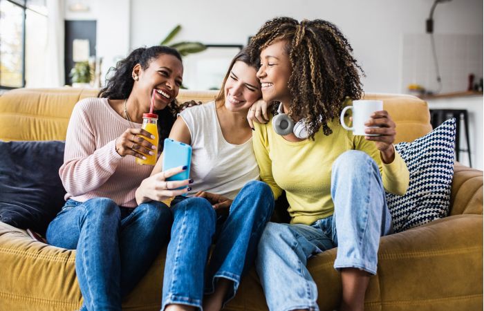 Three roommates smiling and hanging out together in their living room